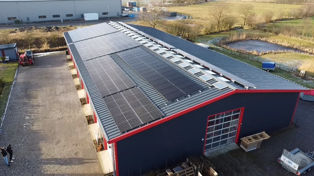 Eine große PV-Anlage auf einem länglichen Gewerbegebäude-Dach.