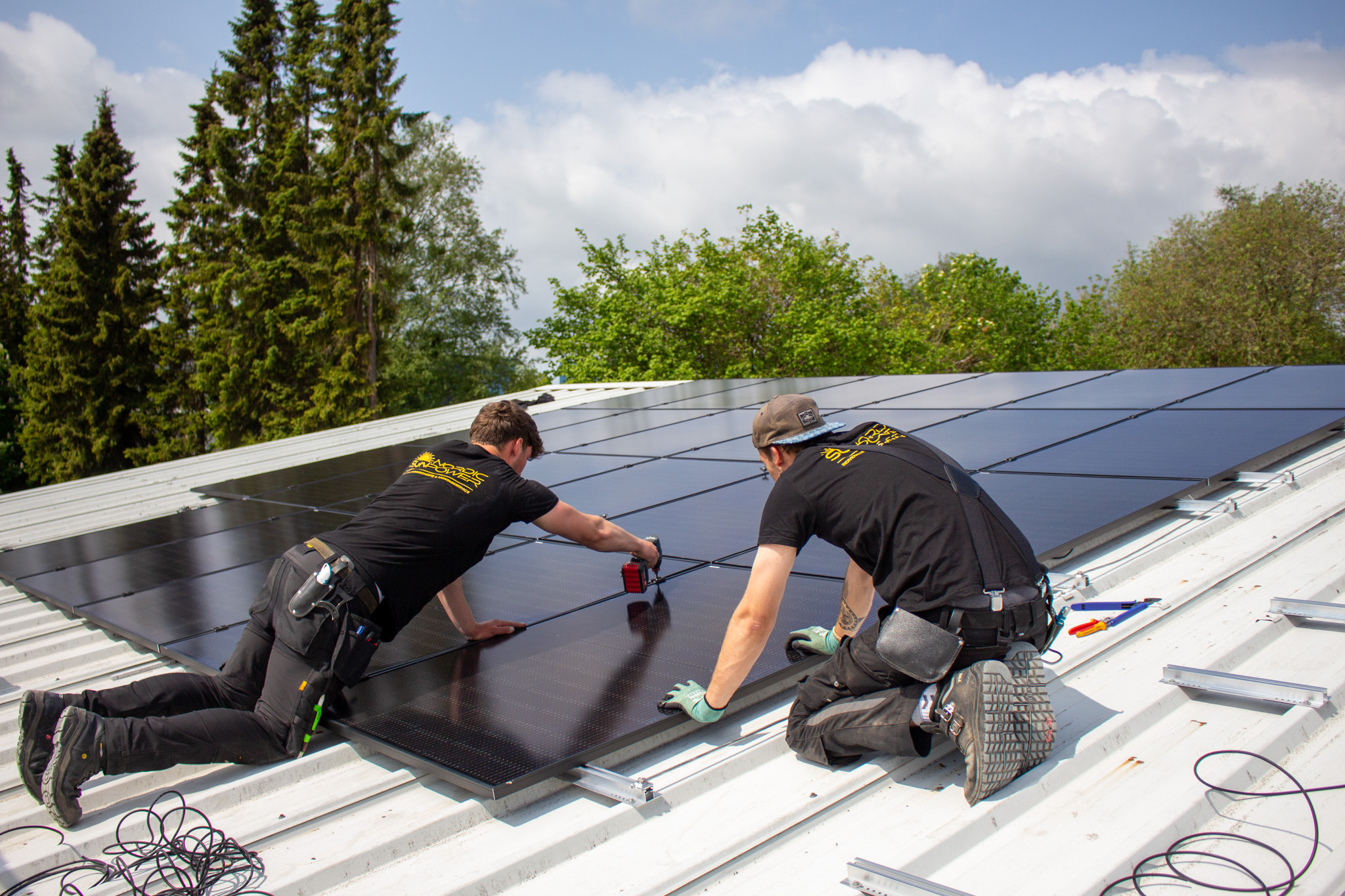 Zwei Handwerker von Nordic Sunpower bei der Montage einer PV-Anlage auf einem Dach.