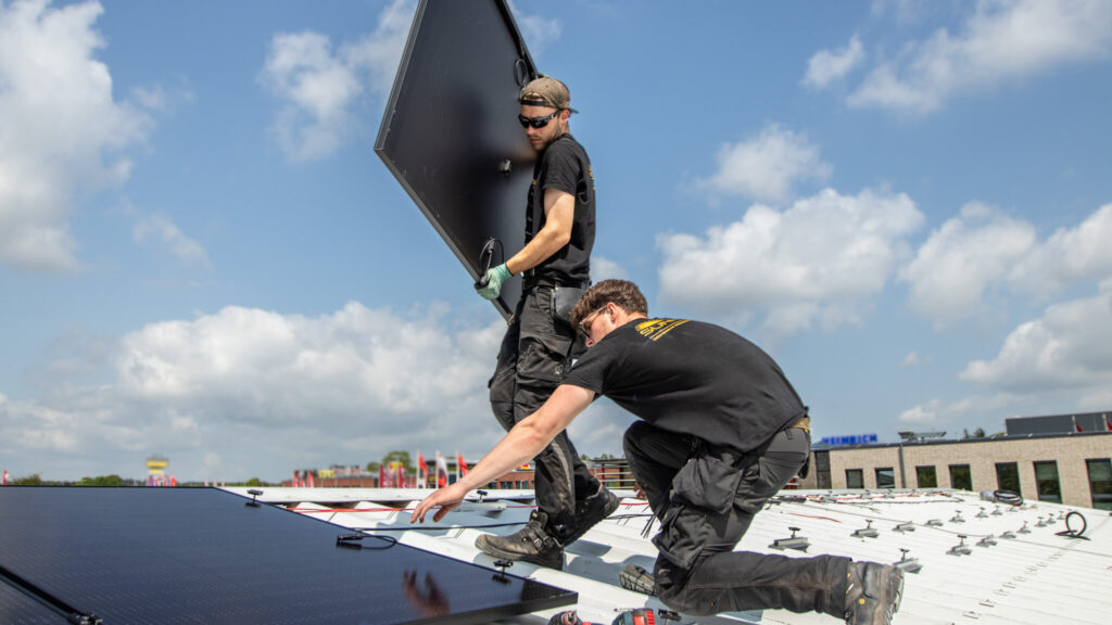 Zwei Monteure von Nordic Sunpower auf einem Hausdach, einer trägt ein Solarmodul.