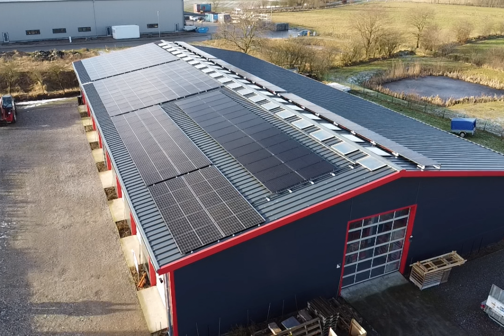 Eine große PV-Anlage auf einem länglichen Gewerbegebäude-Dach.