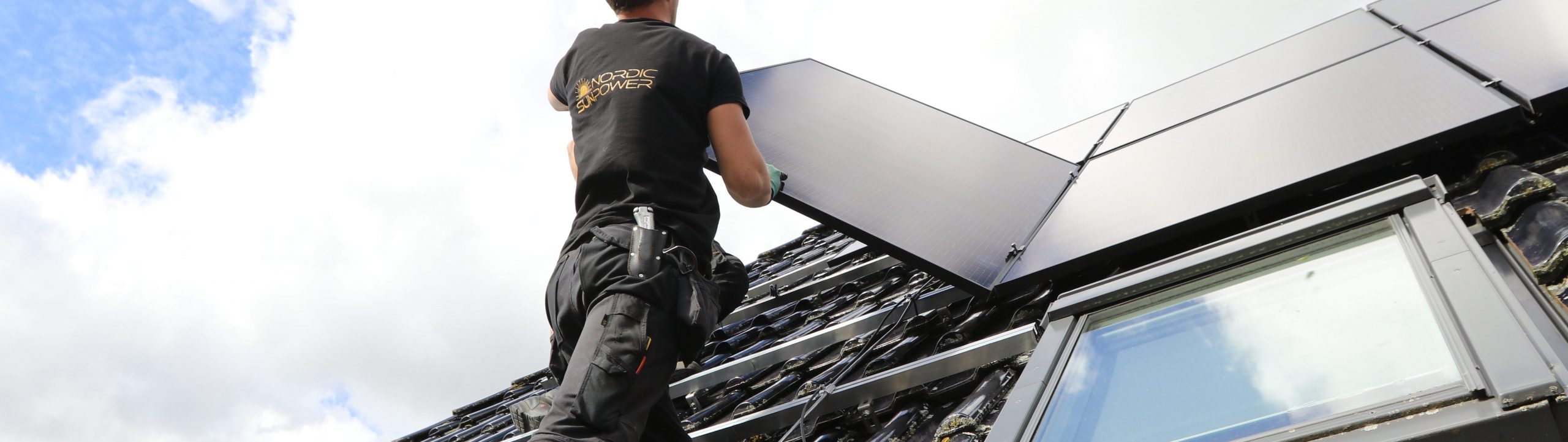 Ein Mitarbeiter von Nordic Sunpower montiert ein Solarpaneel auf einem Hausdach.