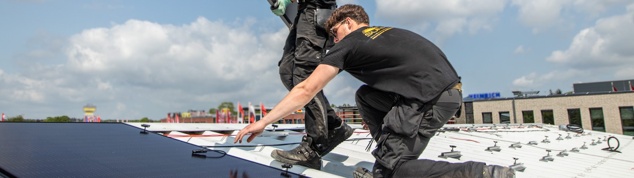 Zwei Monteure von Nordic Sunpower auf einem Hausdach, einer trägt ein Solarmodul.